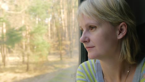 retrato de una mujer joven que viaja en un tren mirando por la ventana los rayos del sol la iluminan