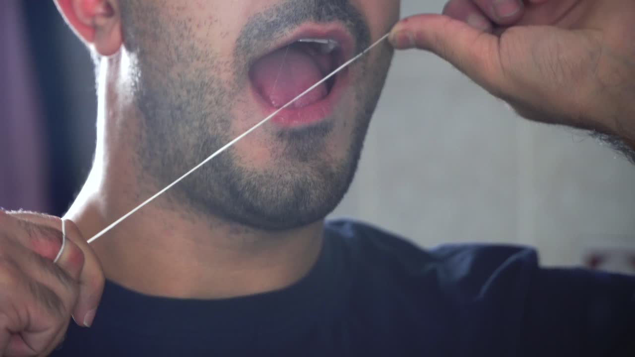 hombre que limpia los dientes con hilo dental