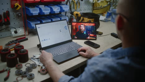 man monitoring real-time stocks, exchange market charts on laptop and smartphone with green chromakey mockup in workshop. video template with placeholder for application. close up. vertical shot.