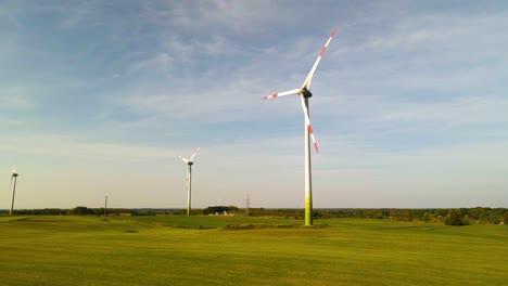 tomada de drones de las turbinas eólicas trabajando y generando energía eléctrica verde en un amplio campo verde en un día soleado, uso de recursos renovables de energía
