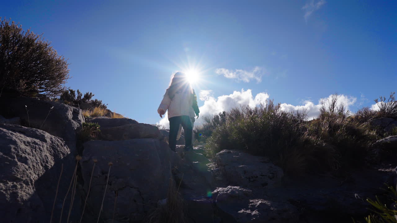 A mother leads her child on an exciting hike through a rocky, sun-drenched landscape. The scene is full of joy, exploration, and the beauty of the outdoors