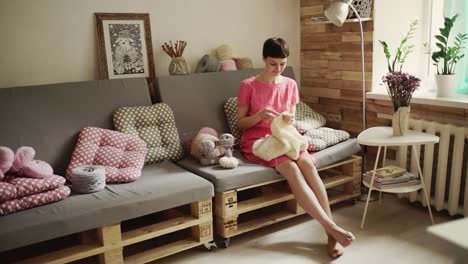 Brunette-woman-sitting-on-couch-and-knitting-woolen-sweater.-Stylish-woman-hobby