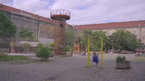 Young-caucasian-girl-swings-in-park-alone,-long-shot