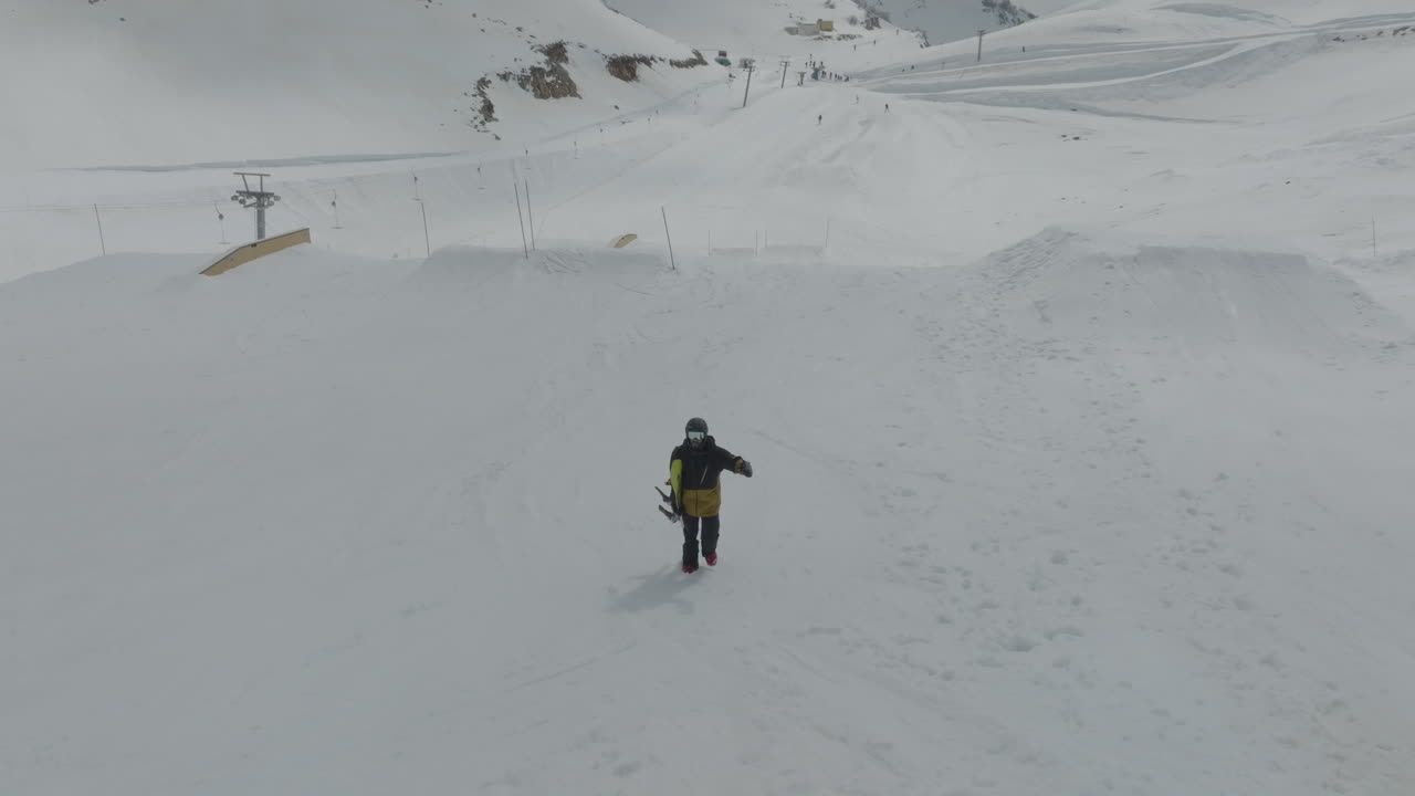 Snowboarder holding snowboard and walking uphill the pistes on the snowy slopes of Mount Hermon, Golan Heights, Israel