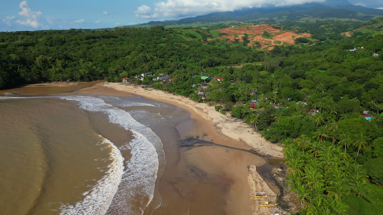 Rising aerial of Quinawan Beach in Mariveles, Bataan, showing turquoise waters rolling onto the sandy shore, with big waves creating white foam patterns along the coastline