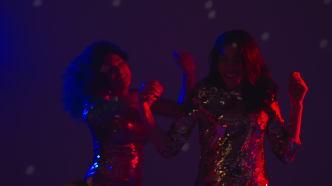 Close Up Of Two Women In Nightclub Bar Or Disco Dancing With Falling Gold Confetti