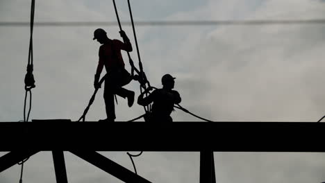 construction workers silhouetted against a cloudy sky