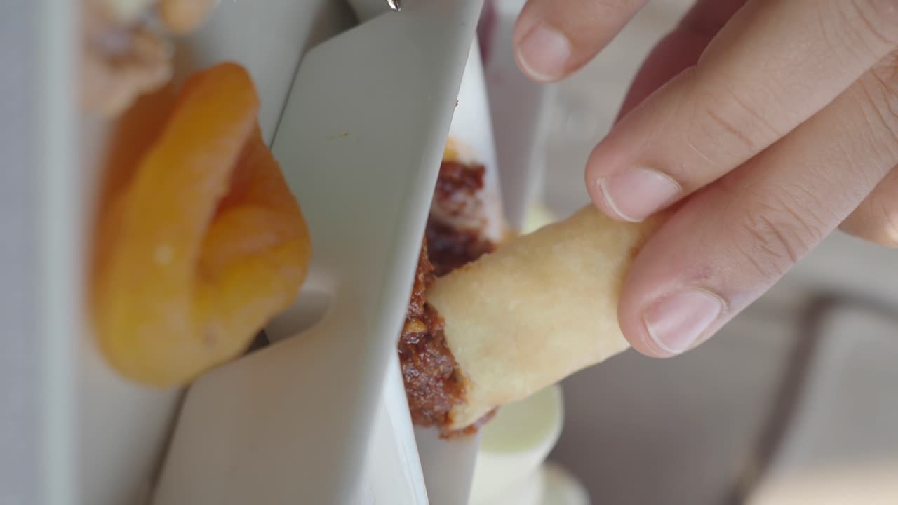 Close-up of a hand dipping a pastry into a food spread
