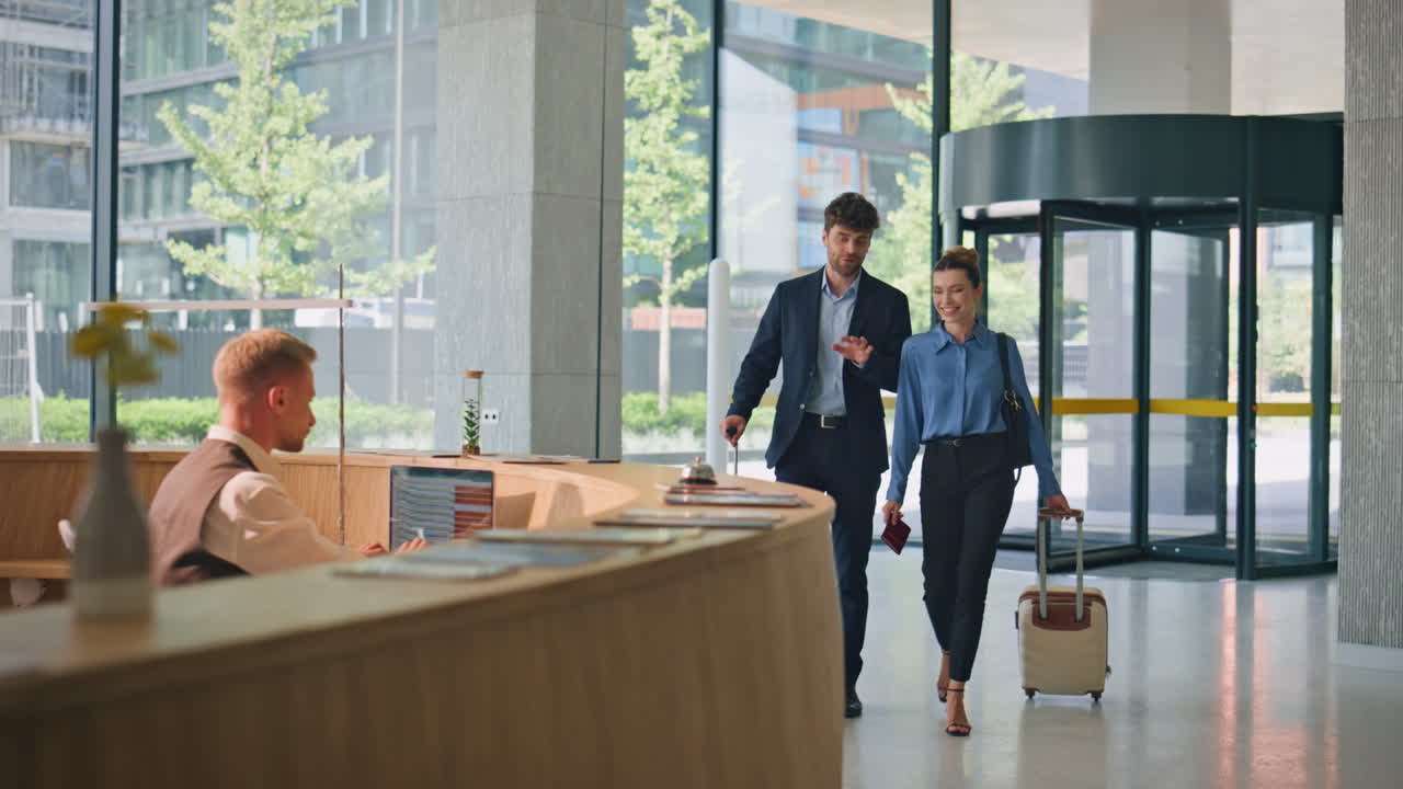 Uomini d'affari che fanno il check-in in hotel durante un viaggio. Receptionist sorridente che saluta al bancone.