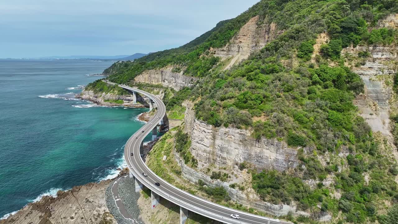 Sea Cliff Bridge and road winding through coastal cliffs above rocks and turquoise waters