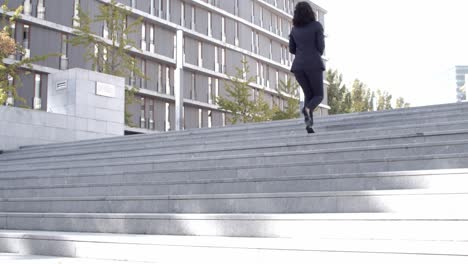 successful curly businesswoman going upstairs