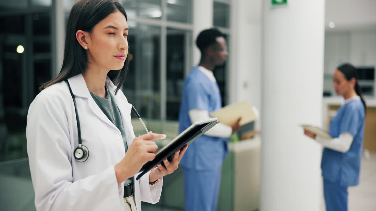 Doctors in a hospital hallway reviewing medical data on a tablet