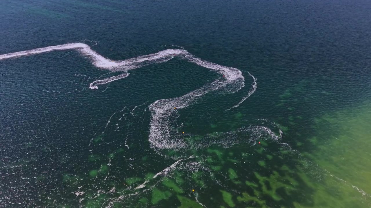 Waves created by watercraft move across a body of water on a sunny day