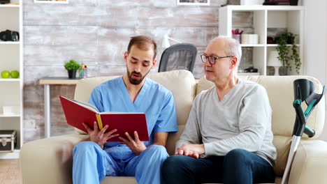 social worker reading a book to an old disabled man in nursing home