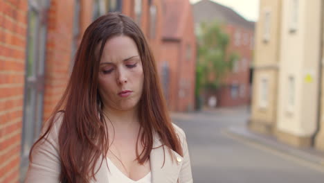 stressed and worried woman outdoors with financial worries about cost of living crisis debt and paying bills looking at mobile phone on city street