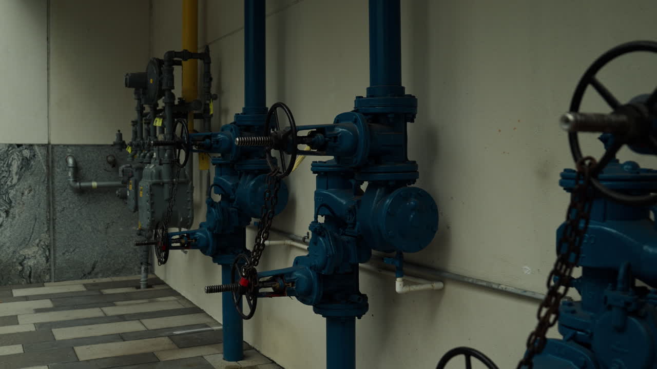 Area industriale di servizio con tubi antincendio, valvole di controllo, manometri e infrastrutture idrauliche con codice colore