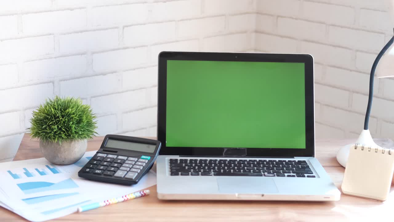 Modern Workspace with Laptop, Calculator, and Green Screen