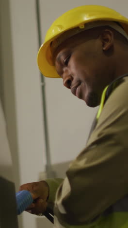 african american male worker wearing safety suit with helmet in warehouse