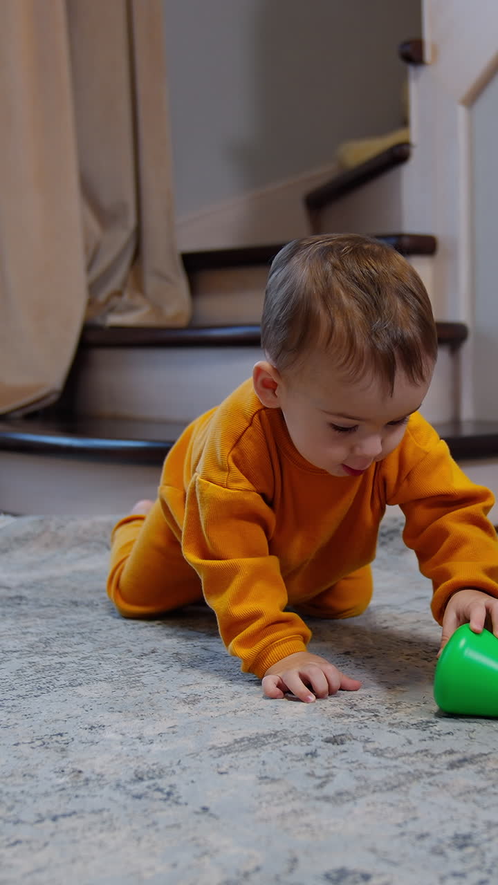 Child crawls up to a toy pyramid and takes the top of it. Baby sits on his knees looking up with curiosity. Vertical video