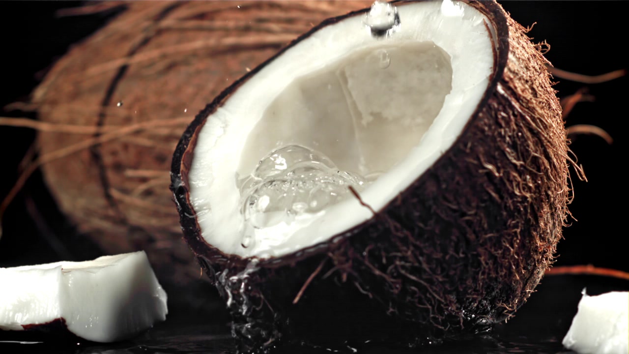 Slow Motion Water Dripping into a Halved Coconut