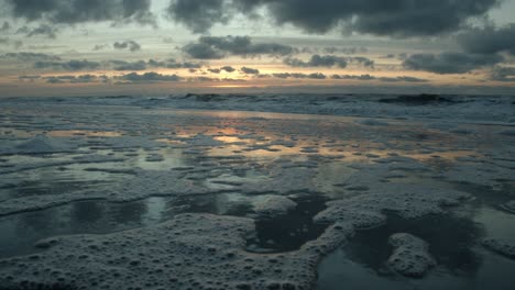 sunset over the north sea on sylt with wet sand in the foreground in which the sun and the clouds are reflected