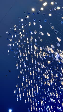 blue and clear unique chandelier. a collection of teardrop-shaped lights hanging from the ceiling, creating a stunning visual display in a modern space