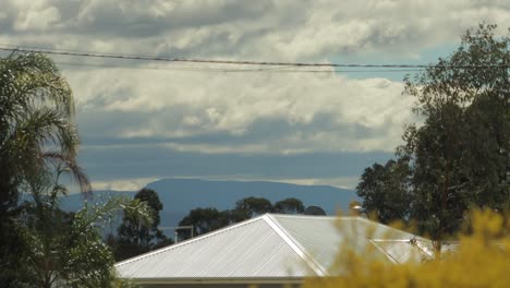 Große-Rollende-Wolken-Ziehen-über-Den-Berg-Mt.-Wellington,-Sonne-Auf-Blechdach,-Windiger-Tag,-Australien,-Victoria,-Gippsland,-Maffra