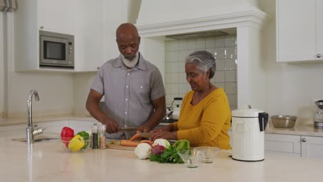 Pareja-De-Ancianos-Afroamericanos-Cortando-Verduras-Juntos-En-La-Cocina-De-Casa