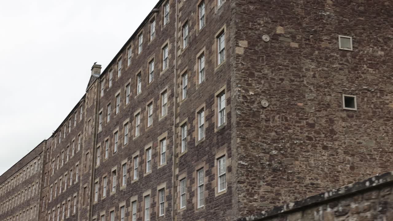 Slow establishing shot of antique tenement buildings at New Lanark