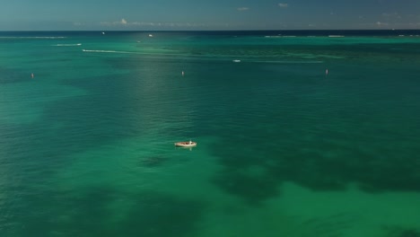 Aerial-shot-focused-on-a-small-fisherman´s-boat,-standing-anchored-near-modern-resorts