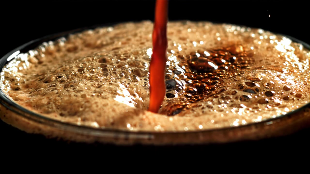 Nærbillede af cola, der hældes i et glas med boblende skum