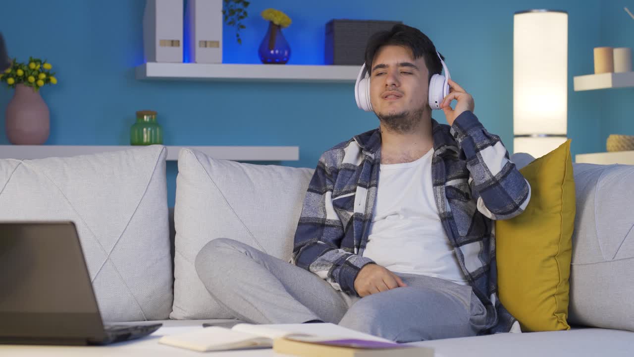 밤에 소파에서 음악을 듣는 남자. 즐겁고 행복합니다.