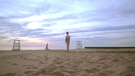 Hombre-Y-Mujer-De-Pie-A-Distancia-En-La-Playa-Al-Amanecer.-Pareja-Playa-Amanecer