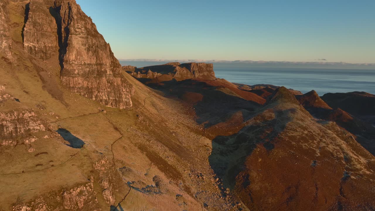 Guglie e scogliere franose che si sgretolano nella luce invernale del primo mattino con una lenta rivelazione orbitale della costa più ampia oltre