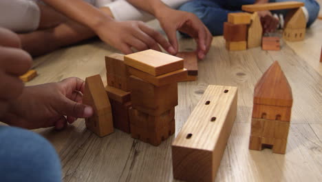 mother and children playing with building blocks in bedroom