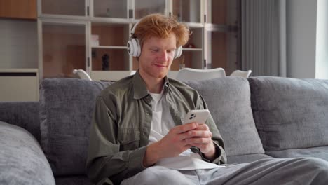 young irish ginger man in headphone doing video call using smartphone