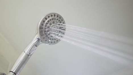 male hand flips a switch on the running shower head to switch between the different jet settings