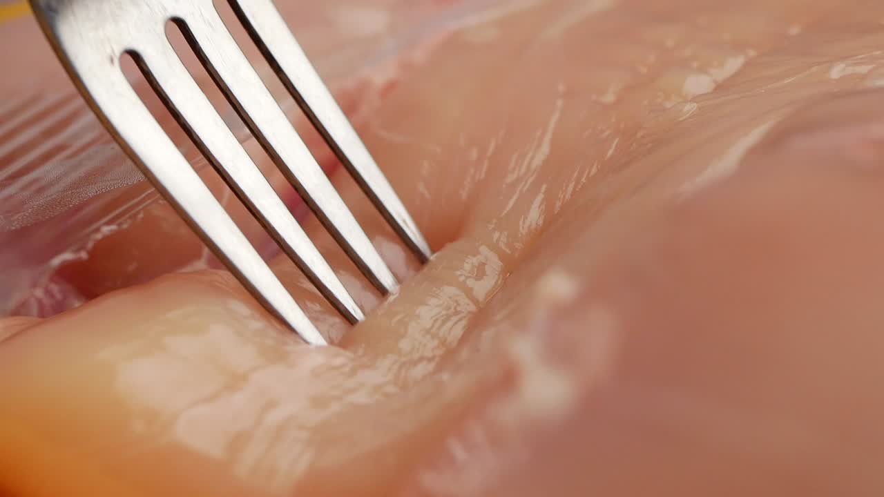 Raw chicken with a fork
