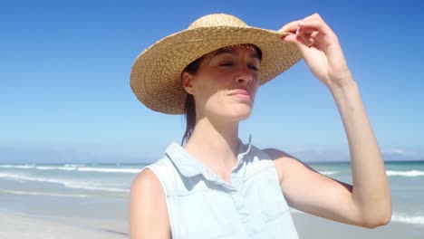 beautiful woman wearing hat while walking at beach