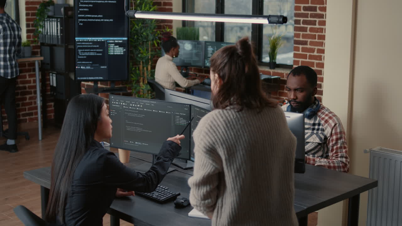 Software programer pointing pencil at source code on computer screen explaining algorithm to coworker