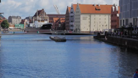 man sailing on pedal boat in motlawa river with view of st. mary's church in old town gdansk, poland. - pan left shot