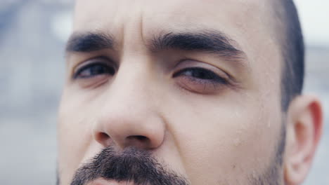 close-up view of the sweaty face of the male boxer during a training outdoors an abandoned factory on a cloudy morning