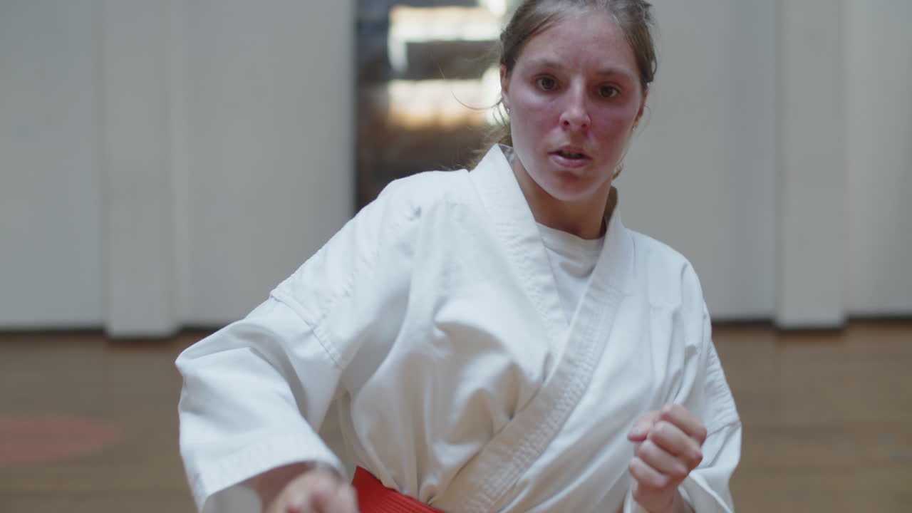 체육관에서 차기를 연습하는 기모노를 입은 심각한 소녀의 추적 샷