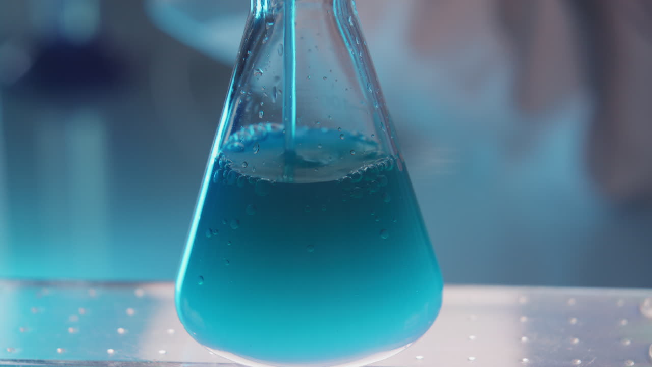 Close Up of Pouring Blue Liquid into Laboratory Flask during Research