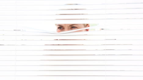 Woman-peering-through-roller-blind