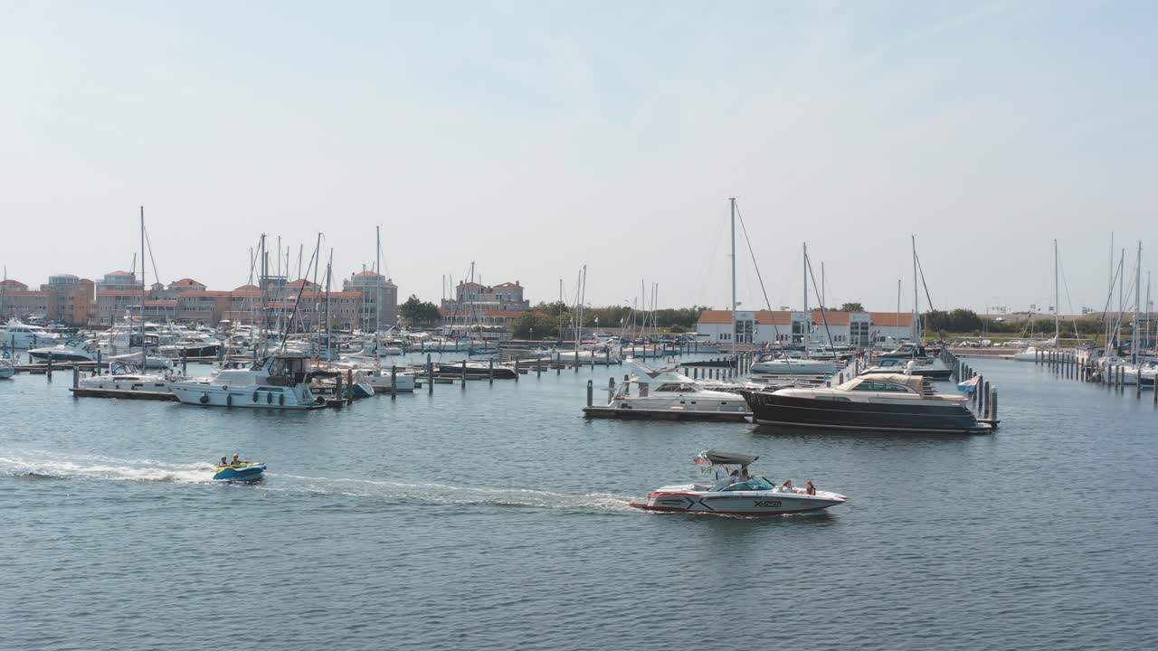 시네마틱 드론 - 화창한 날 25p에 항해 보트와 함께 백그라운드에서 정박지에서 운전하는 두 척의 보트의 공중 샷