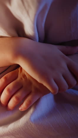 playful little kid hugs huge soft striped pillow by crosses hands in semidark bedroom glowed by night lamp and shadow corner in evening extreme closeup slow motion
