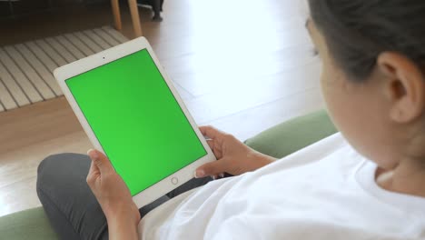 mujer india sentada en el sofá y mirando el dispositivo de computadora tableta con pantalla verde en blanco, maquillaje, entretenimiento, copyspace, freelance, plantilla, tiempo de ocio, concepto de tecnología.