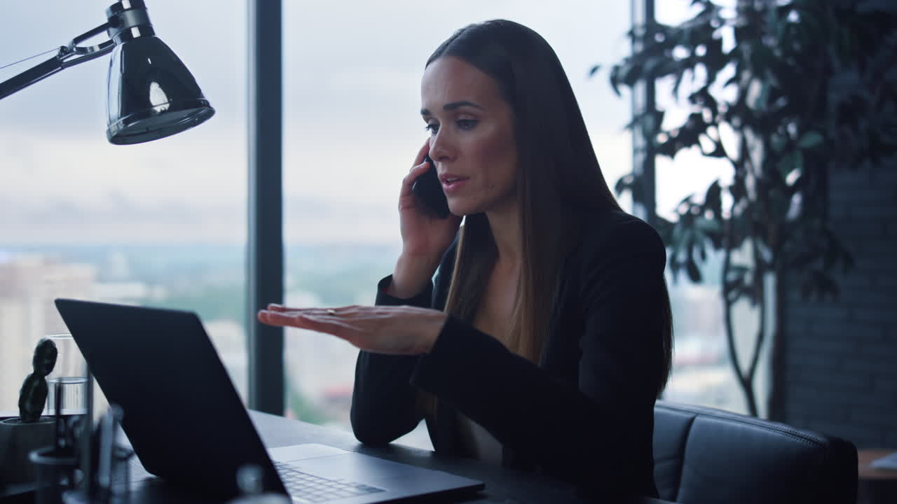 mujer de negocios hablando en el teléfono inteligente en la oficina. mujer mirando la pantalla del portátil