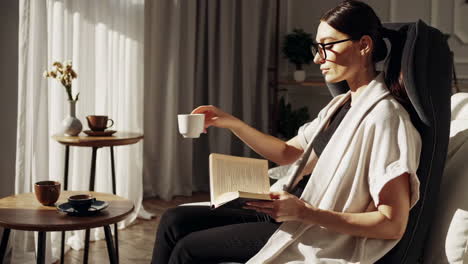 woman relaxing and reading a book at home with a cup of coffee